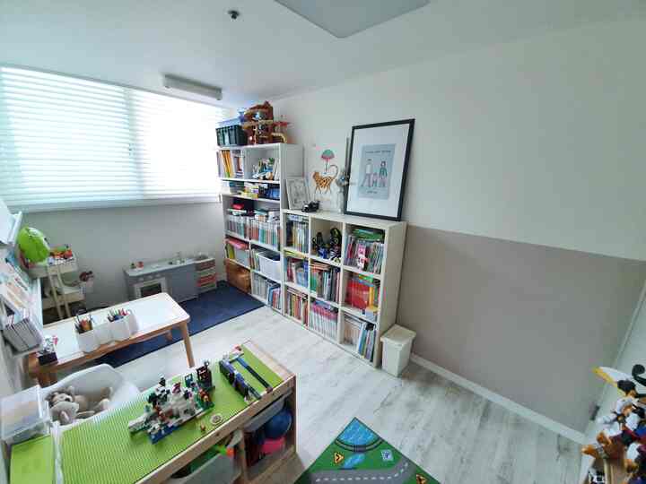 White and natural toned kids' room featuring organized storage units and a lego desk, creating a compact and tidy space