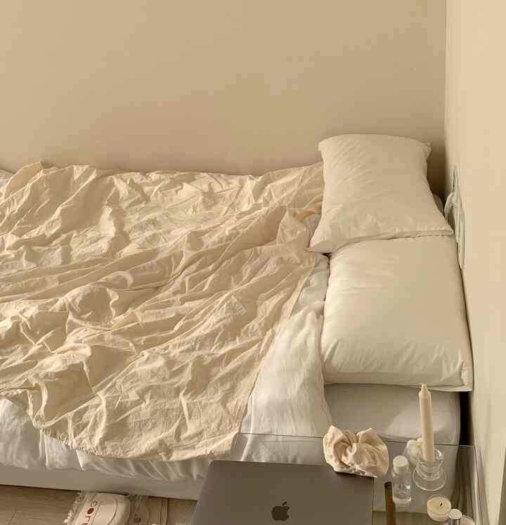 Ivory and white toned bedroom featuring pillows and blanket arranged simply creating cozy atmosphere