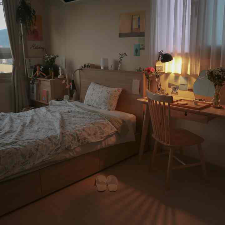 Cozy natural-toned 6-pyeong studio bedroom featuring wooden bed and desk, soft floral bedding and curtains with warm sunlight