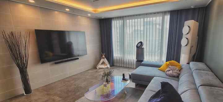 Modern living room with warm beige tiled wall and gray sofa, large windows with curtains brighten the cozy space