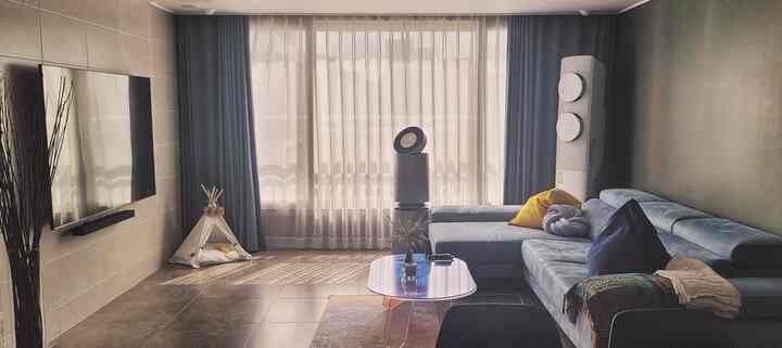 Blue and wood tone living room featuring sectional sofa and transparent coffee table with a modern, tidy atmosphere