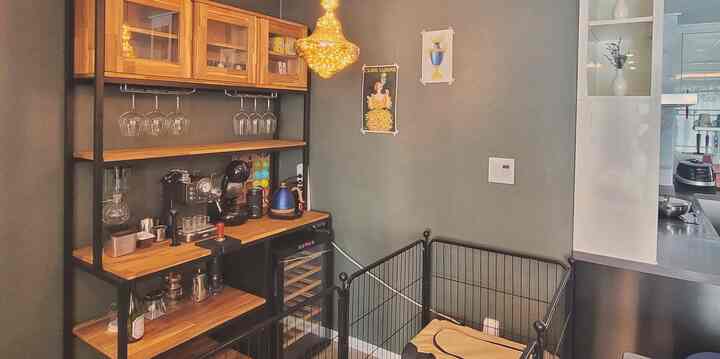 Home cafe space next to kitchen featuring black metal frame and wood tone shelves, cozy interior with pet house for a dog