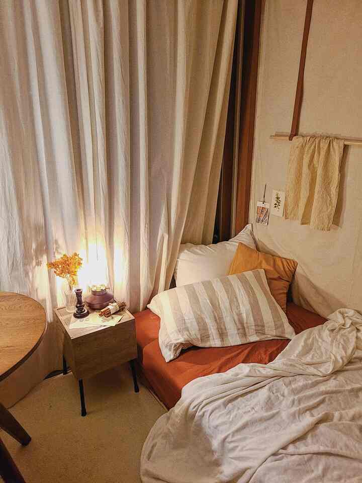 ナチュラルな色調と木目調のワンルーム寝室、ナイトテーブルと枕が配置された落ち着いた空間