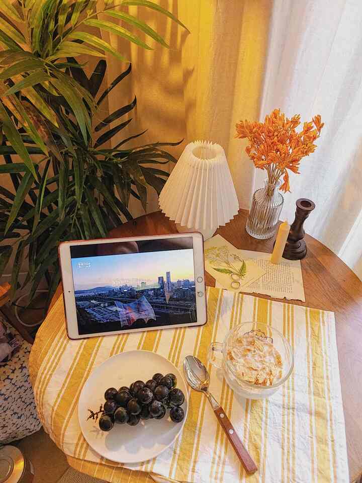 Beige-toned curtains and round table with iPad and snacks create a natural home cafe atmosphere
