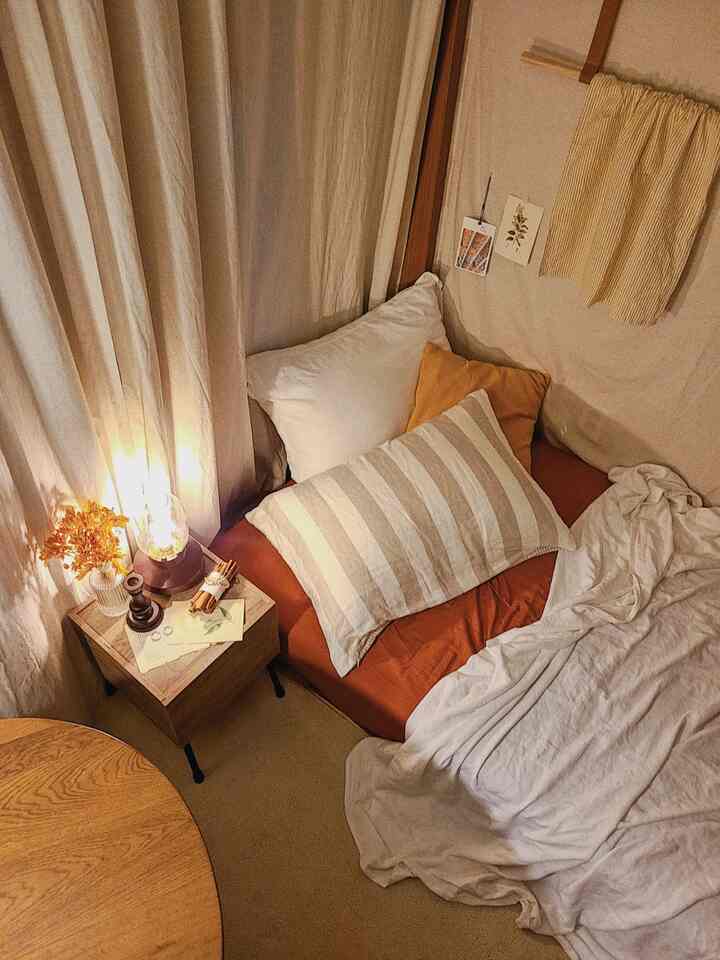 Cozy bedroom in warm ivory and brown tones, featuring a nightstand with mood lighting in a compact studio apartment