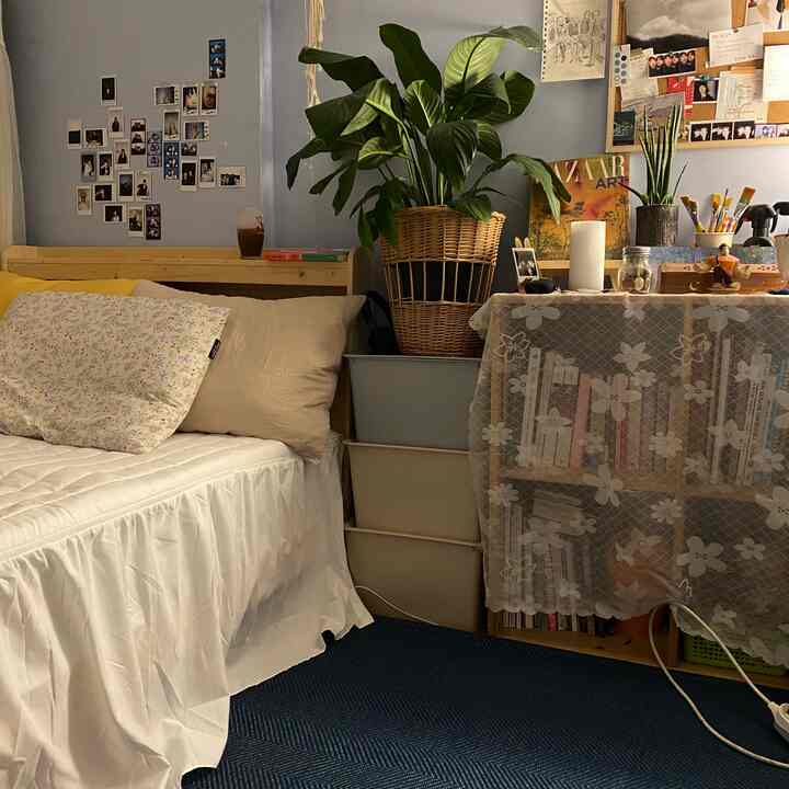 Soft white and natural tone bedroom featuring floral pillows and lush plants creating a cozy atmosphere