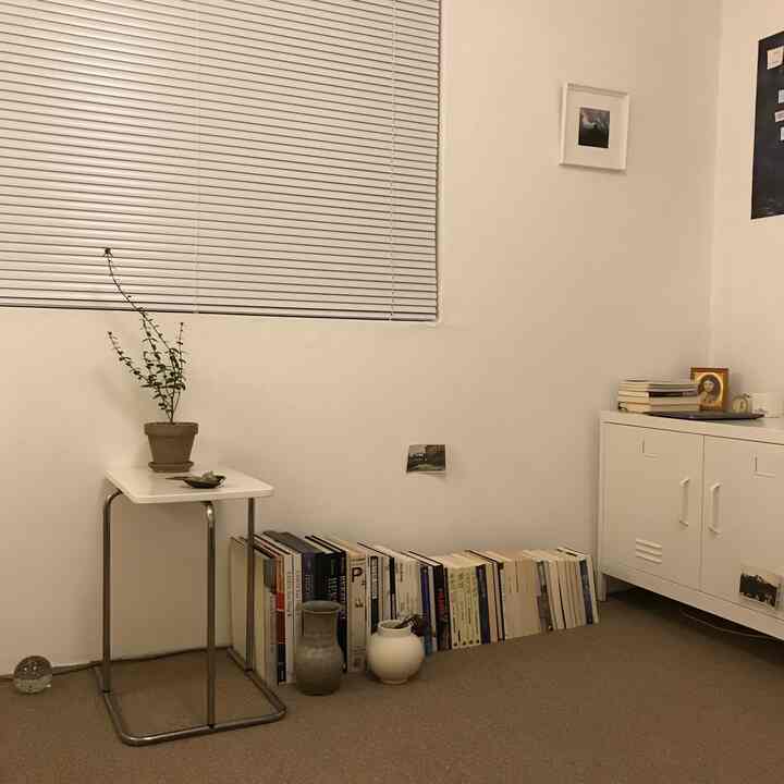 A white and natural toned study featuring a side table, cabinet, and neatly arranged books with a calm atmosphere