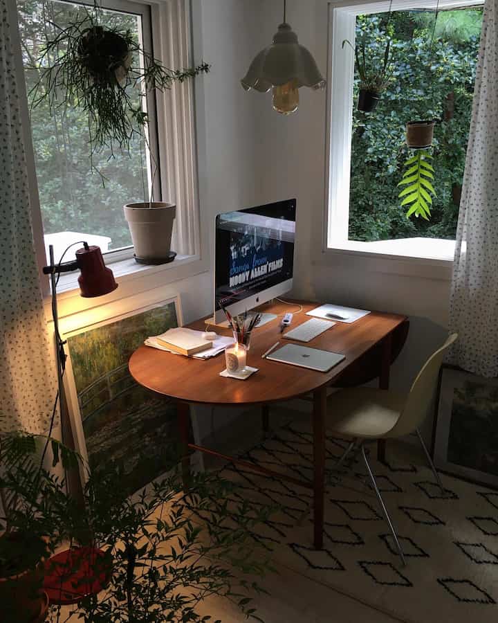 Cozy small home office featuring wood tones and green plants, with a wooden desk and office chair harmoniously placed for a comfortable workspace
