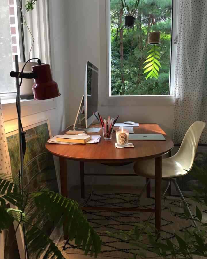 Natural-toned home office featuring a wooden dining table and chair, surrounded by green plants creating a warm and cozy atmosphere