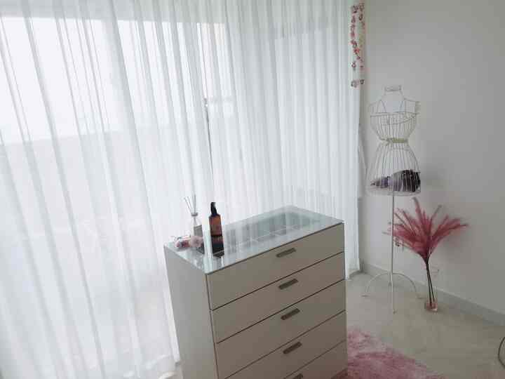White and pink-toned walk-in closet featuring a closet cabinet and sheer curtains creating a cozy storage space