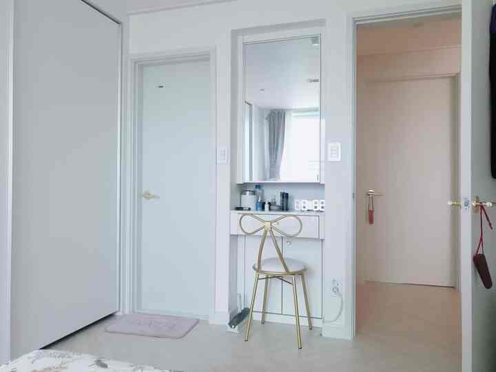 White and gold toned bedroom featuring a gold chair and vanity centrally, creating a spacious tidy atmosphere