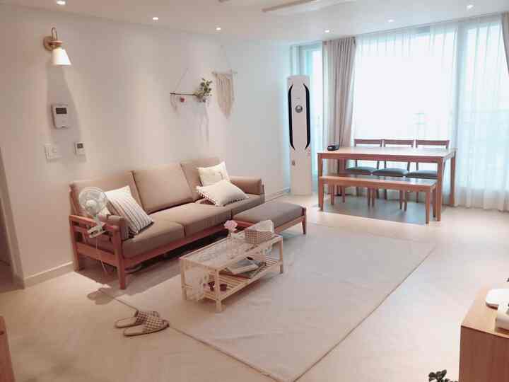Natural tones and white living room featuring a beige sofa and wooden dining table creating a bright, cozy atmosphere