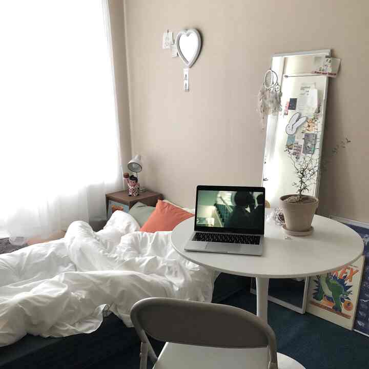 ホワイトとウッドトーンが調和したワンルーム寝室、シンプルな家具配置と自然の要素が映える印象的な空間