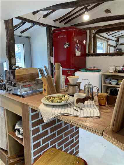 Wood tone and red-themed compact kitchen featuring coffee tools and organized storage, creating a cozy home cafe atmosphere