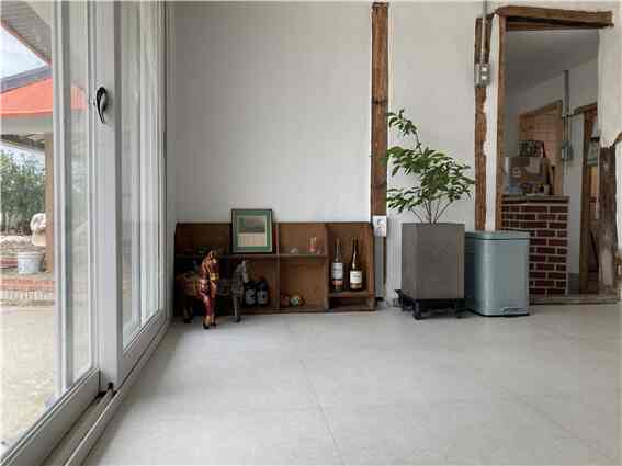 Natural toned small living room featuring wooden shelving and glass door with a simple, vintage atmosphere