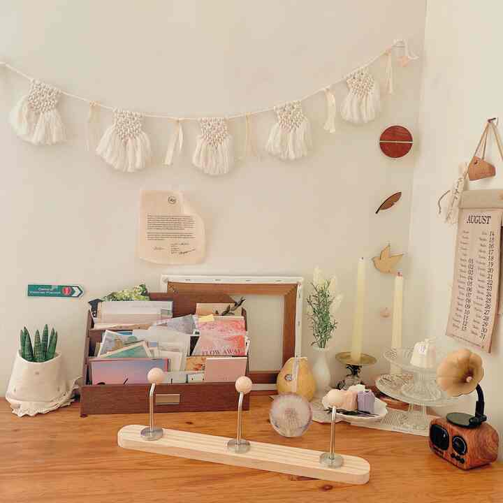 Cozy beige and wood tone desk area featuring a garland mobile and various decorative objects creating warm ambiance