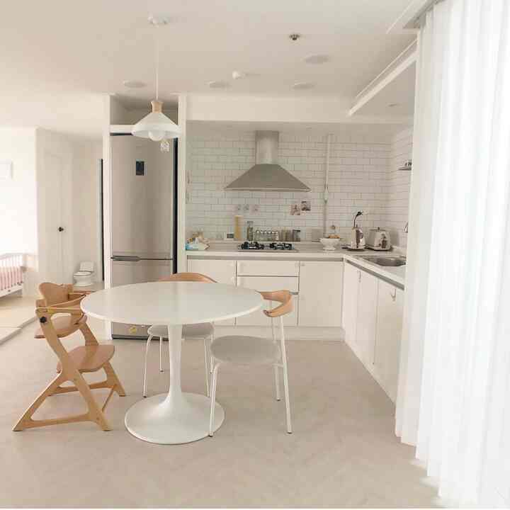 Bright white and wood tone kitchen and dining space designed for living with a baby
