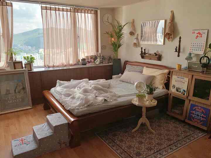 Brown wood-toned bedroom with white linen curtains, vintage dresser, and plants creating a warm, natural atmosphere