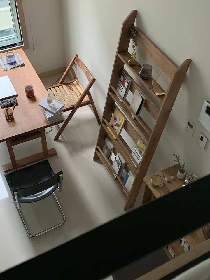 Natural wood tone furniture and folding chairs in a compact studio apartment creating a calm home office space