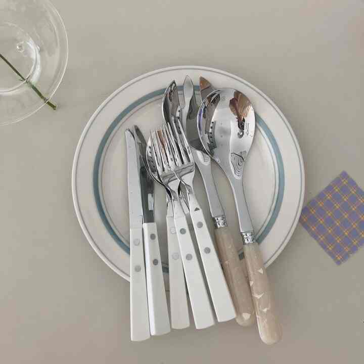 White and blue-toned kitchen setting featuring neatly arranged cutlery on a plate with a clean aesthetic