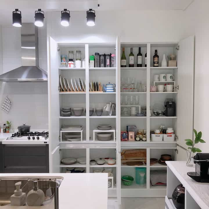 白を基調としたキッチン、整理された収納キャビネットとモダンな調理スペースが調和した清潔感のあるインテリア
