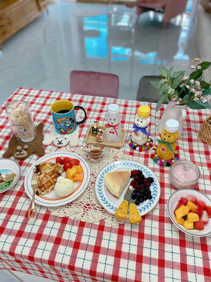 Red checkered tablecloth dining room featuring plates, coffee cups, and bear-shaped bottles in a cozy home cafe setting