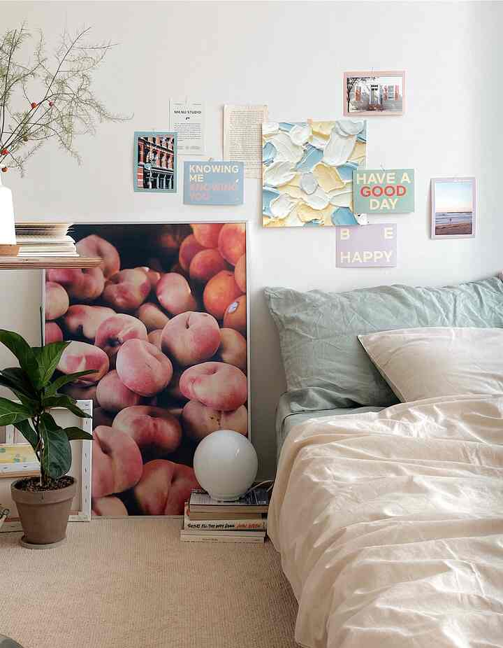 ベージュのナチュラルカラーの寝室、枕と掛け布団カバーを中心に、ポスターと植物が配置された落ち着いた雰囲気のインテリア