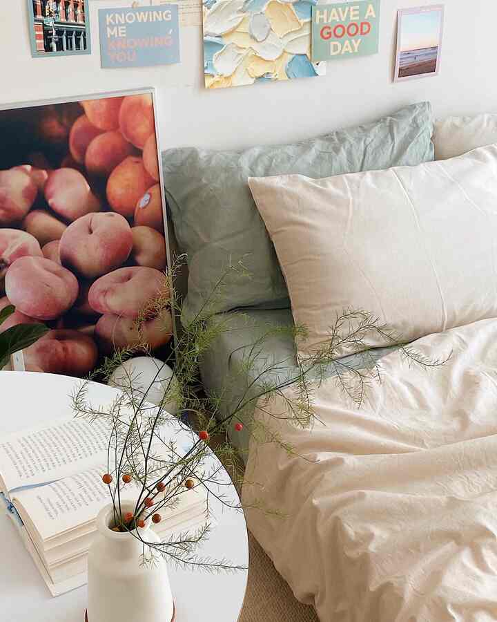 ベージュとミントトーンの寝室空間、掛け布団カバーとソファ、ポスター、植物が配置された雰囲気のあるカフェ風インテリア