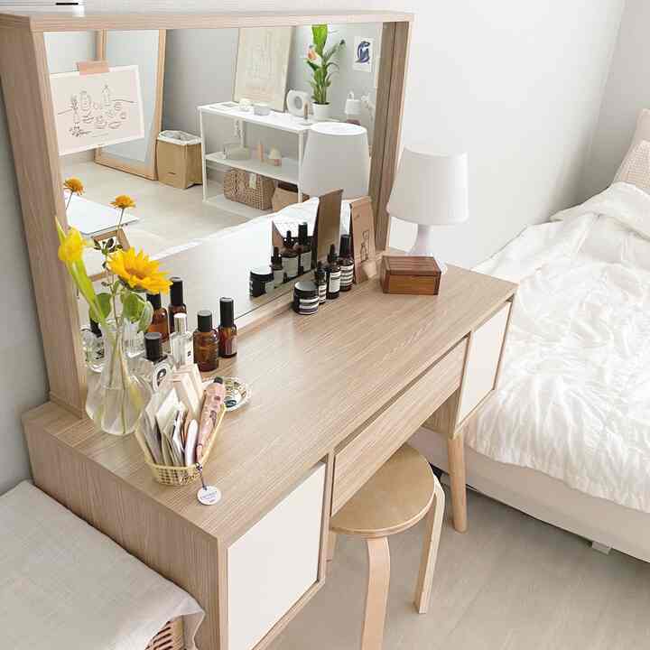 明るい木目調と白が基調の寝室、シンプルな木製化粧台と大きな鏡が配置された雰囲気のあるインテリア