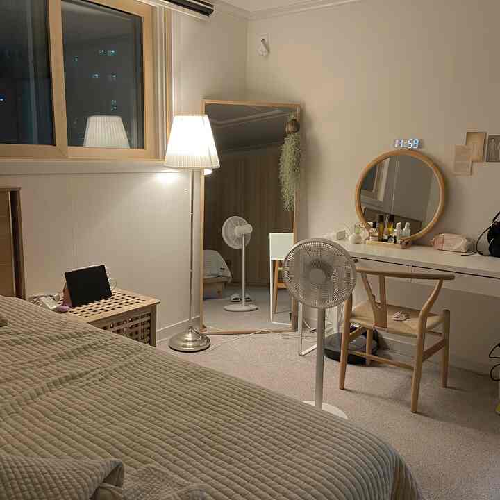 Natural beige-toned bedroom featuring wooden chair with rattan seat, vanity with round mirror, and large floor mirror in cozy atmosphere