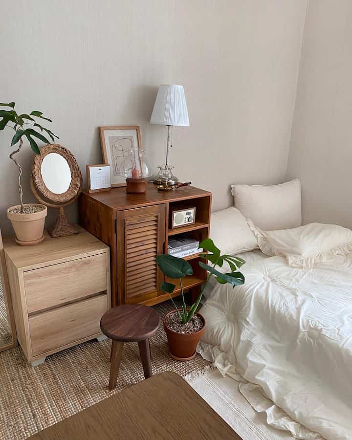 Ivory-toned bedroom with cozy bedding, wood tone nightstand and plants creating a natural modern interior