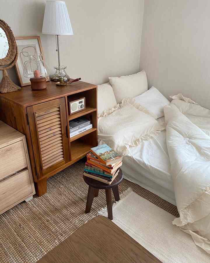 Natural-toned bedroom featuring a nightstand, bed with pillows and duvet cover, creating a cozy interior atmosphere
