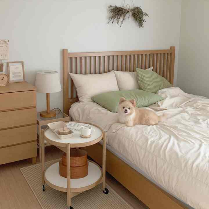 Natural tone bedroom featuring wooden bed with beige bedding and a small dog on the bed, creating a cozy atmosphere