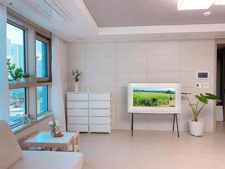 Bright living room in white and ivory tones featuring children's table and chairs by the window, with clean and airy atmosphere