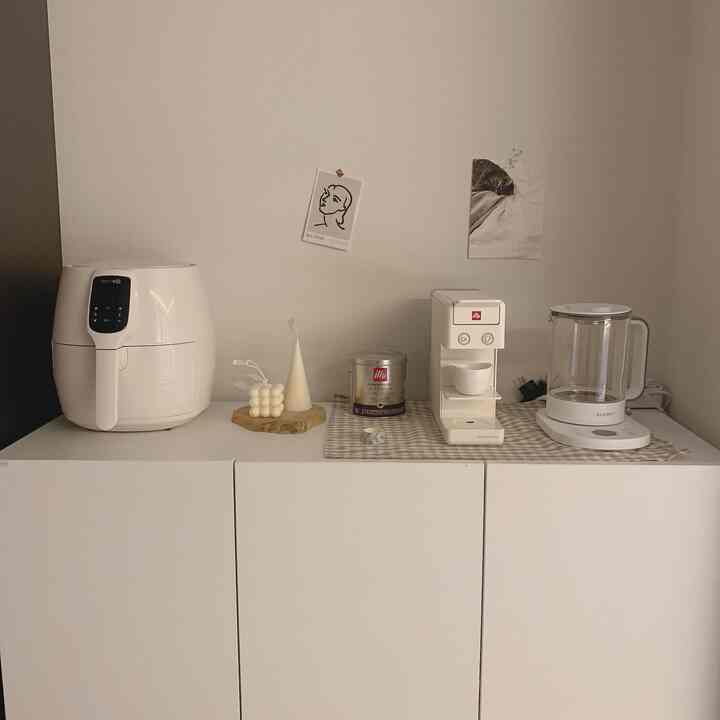 White-toned kitchen space featuring a coffee machine and air fryer on a clean and minimal cabinet surface