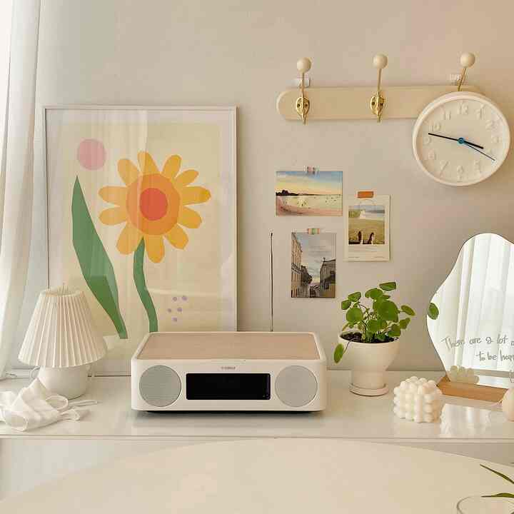 Bright natural-colored table setting featuring audio system, poster, mirror, plant, and clock in a cozy space