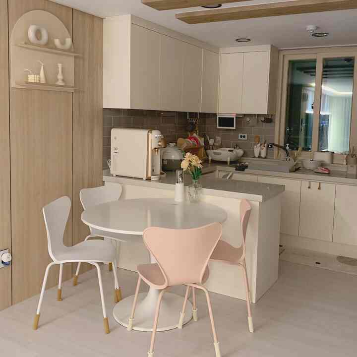 白とベージュのトーンのキッチン、丸いダイニングテーブルと椅子が配置されたナチュラルモダンなインテリア