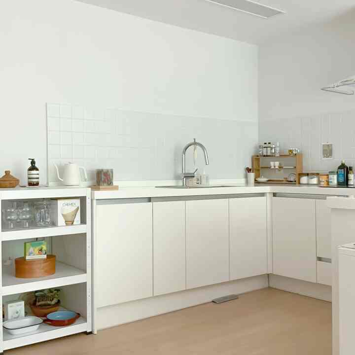 White-toned kitchen featuring simple cabinets and organized storage with a clean and modern atmosphere
