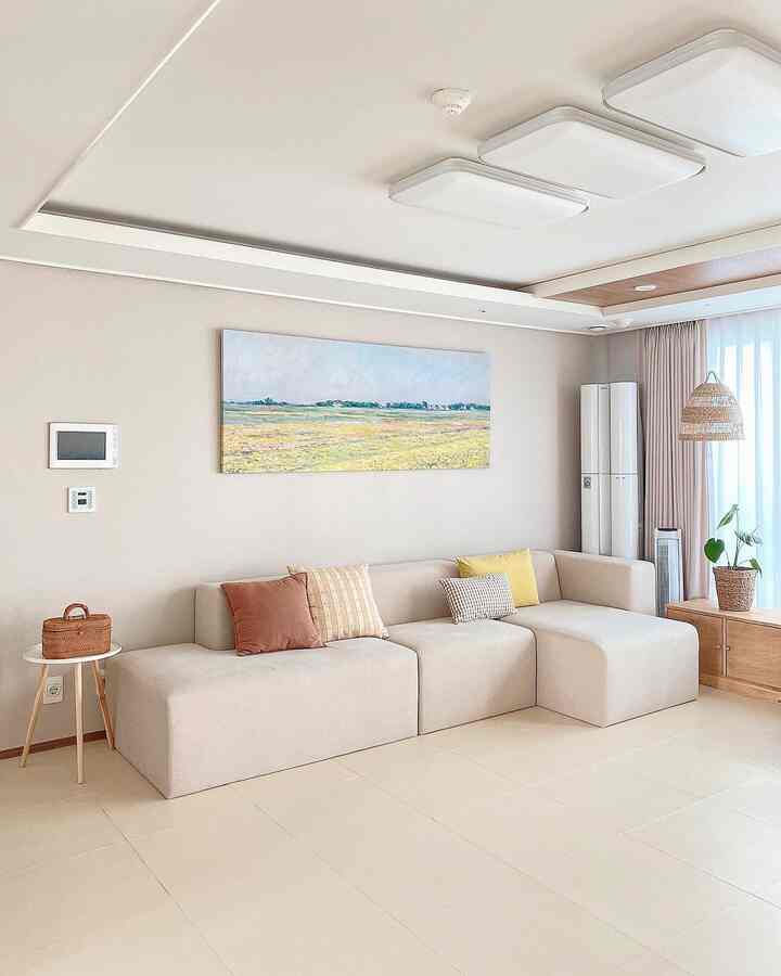 Beige and wood tone living room featuring large sofa, wall art, and curtains creating a cozy atmosphere