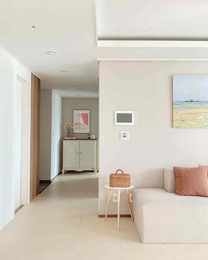 白とナチュラルトーンのリビング、ソファとサイドテーブル、壁のアートが配置された印象的な空間