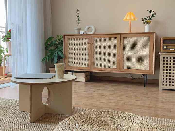 Warm beige toned natural living room featuring wood tone sideboard, rattan rugs, and a round coffee table creating a cozy atmosphere