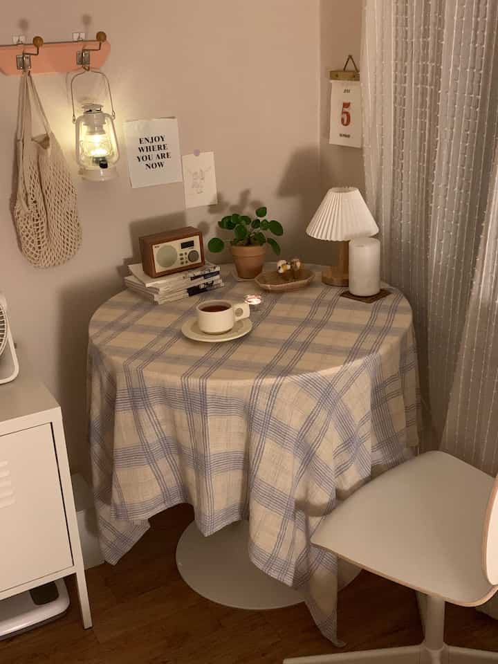 Beige and white toned bedroom space featuring a round table with tea and decor, creating a cozy home cafe atmosphere