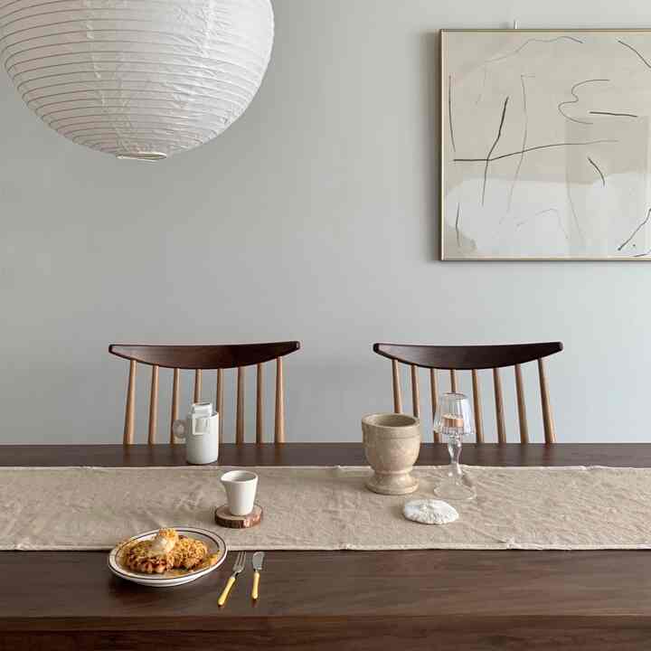 Beige and wood-toned dining room featuring a walnut dining table and chairs in a minimal, cozy setup