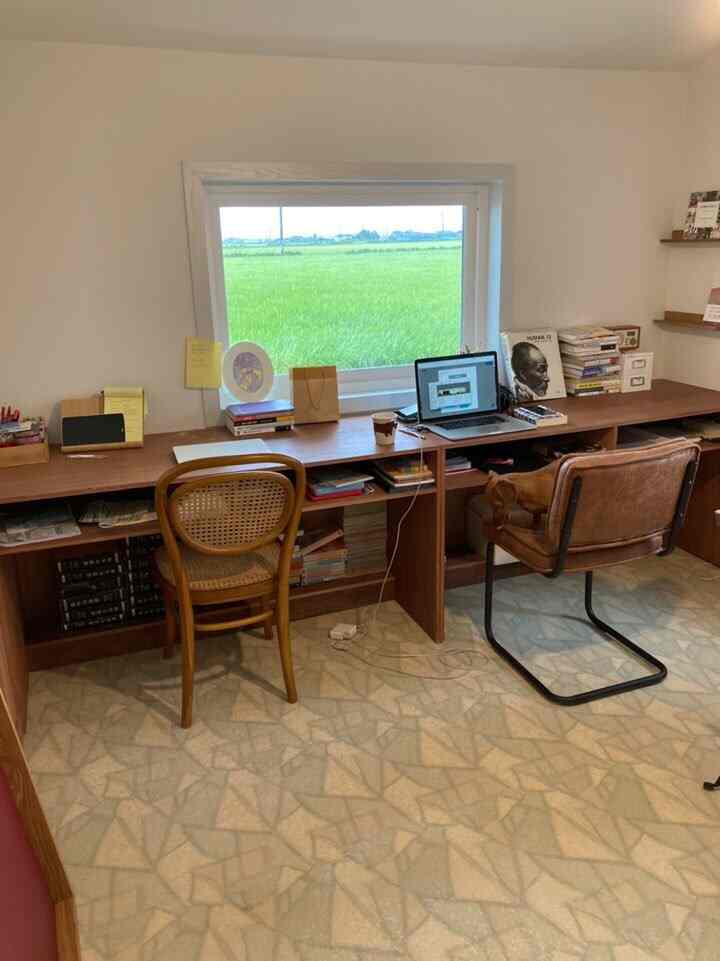 Natural wood-toned small home office space featuring a long desk with two chairs, creating a cozy remote work environment