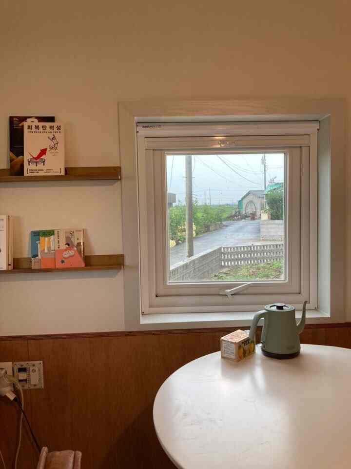 White and wood tone kitchen featuring a round dining table, window, and electric kettle creating a cozy home cafe atmosphere
