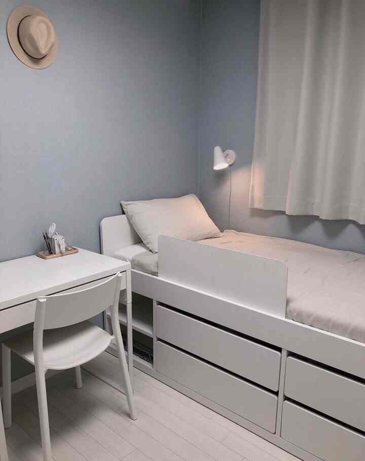White and blue toned kids' room featuring a simple bed frame and desk in a clean minimalist interior