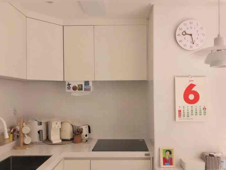 Bright white-toned small kitchen featuring simple modern cabinetry and diverse coffee equipment in a neat layout