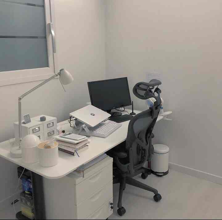 White-toned study room featuring a height-adjustable desk and Aeron chair centrally placed, with a clean home office atmosphere