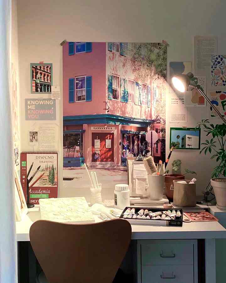 白と木目調の調和が感じられるホームオフィス、壁に大きなポスターがあり、整頓された机が配置された雰囲気のある空間