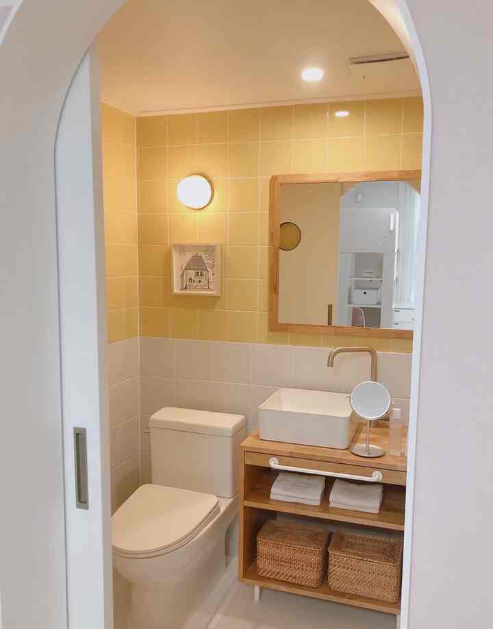 Natural style bathroom with yellow and white tiles, wooden vanity and rattan storage baskets positioned in a cozy setting